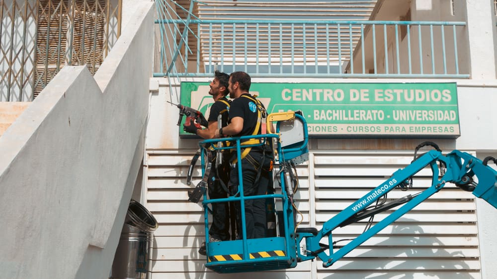 Dos técnicos de Frimec montando el conducto de extracción desde plataforma elevadora